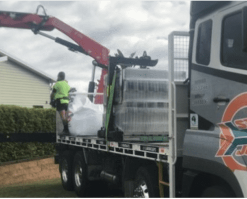 Steve jones delivery truck with crane delivering over residential hedges