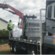Steve jones delivery truck with crane delivering over residential hedges