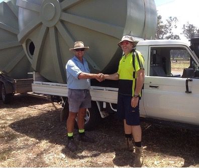 Workers shaking hands in front of ute towing a large water tank
