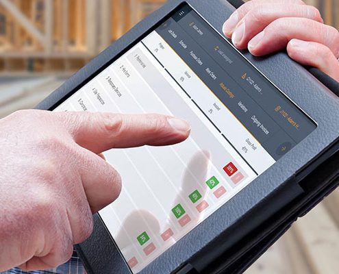 Buildxact software on tablet with construction building in the background