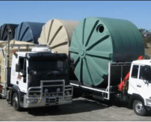 Two trucks loaded with multiple poly water tanks from Capital Tanks