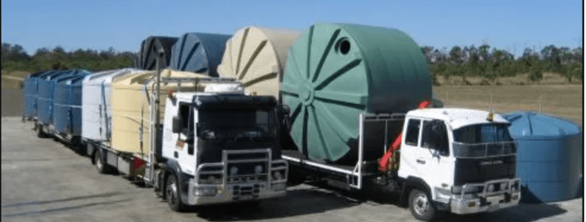 Two trucks loaded with multiple poly water tanks from Capital Tanks