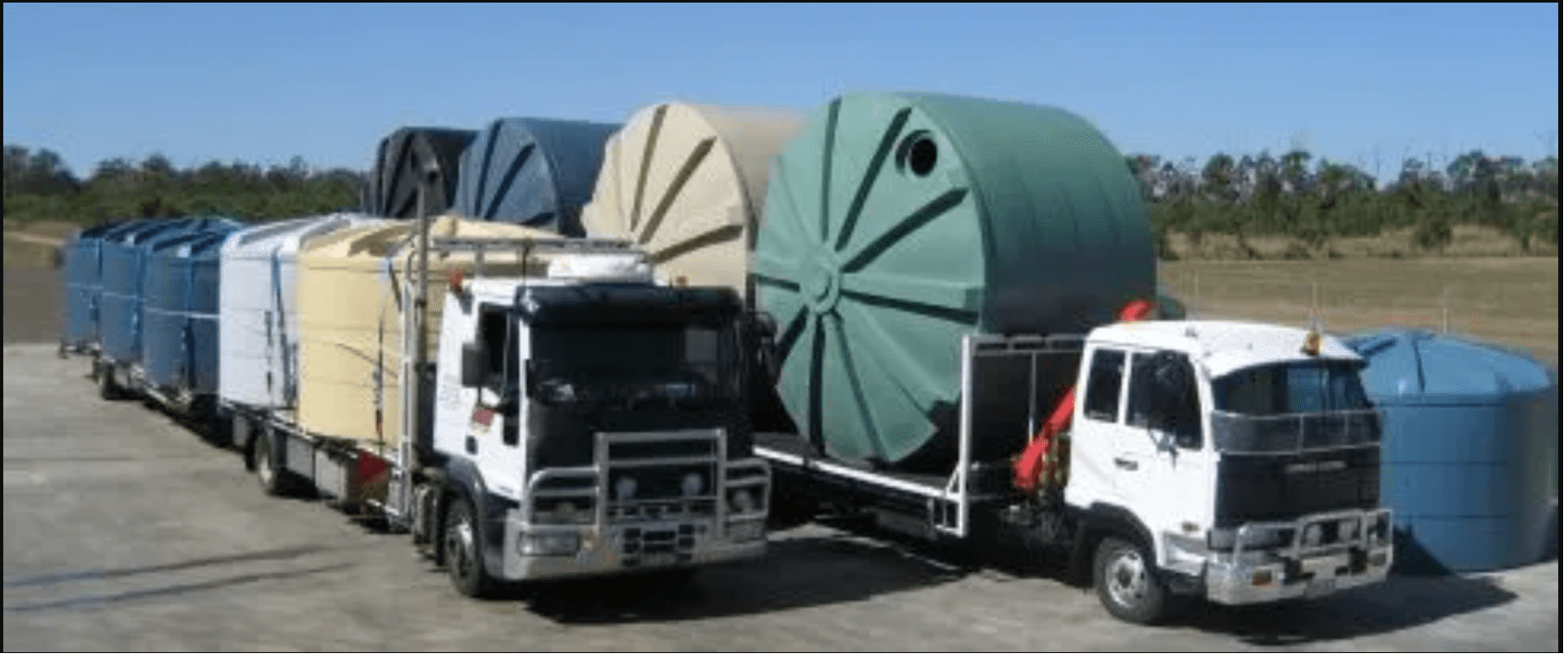 Two trucks loaded with multiple poly water tanks from Capital Tanks