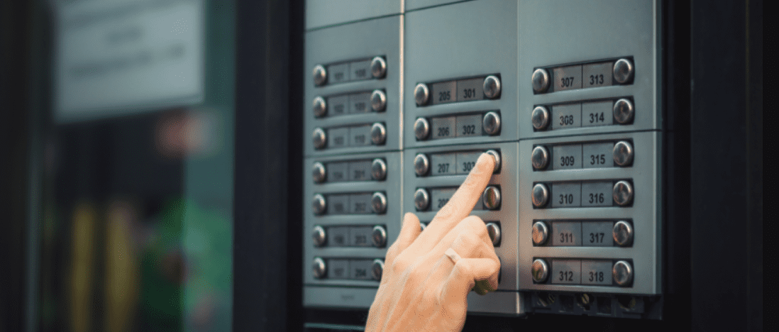 A finger pressing an apartment call button on the buzzer