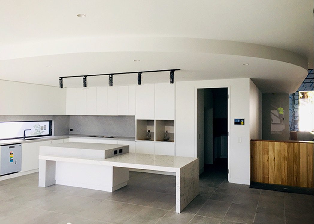 A kitchen in the middle of construction with a completed white curved bulk head from CHAD