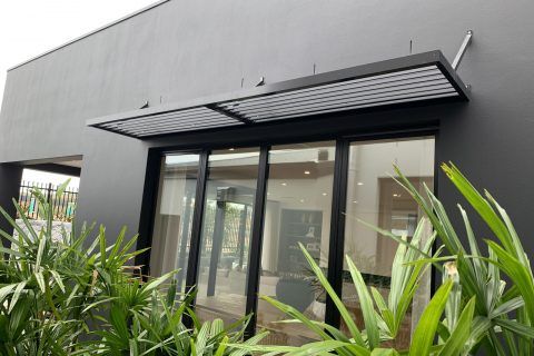 Black external office building with black windows and palm plants in front