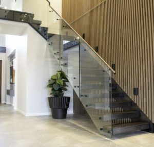Multi level black and dark timber stairs with a glass balustrade and silver handrail.