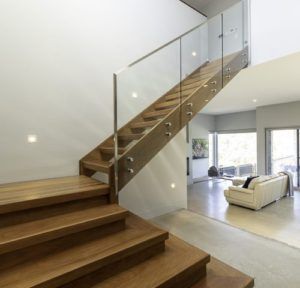 Two story timber stairs with glass balustrade and open white living room