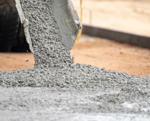 Close up of a cement tube pouring wet cement onto the construction site
