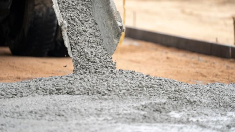 Close up of a cement tube pouring wet cement onto the construction site