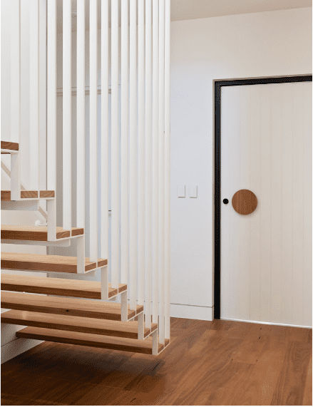 Stair Lock hampton style floating stairs with timber treads and white timber vertical balustrade that matches the timber front door.
