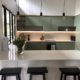 White kitchen with green cabinets and black accented lights and kitchen island stools