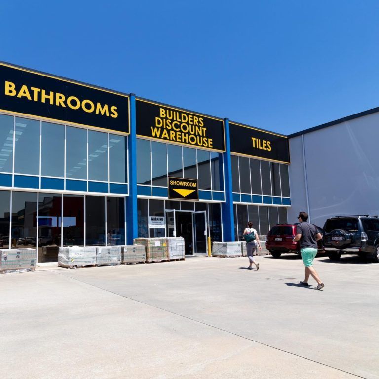 Customers walking across carpark to a big warehouse showroom. Black background with bright yellow text “Builders Discount Warehouse”