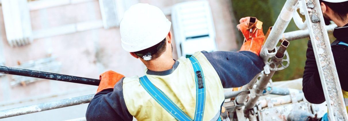 Employees with harnesses standing on scaffolding up high