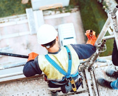 Employees with harnesses standing on scaffolding up high