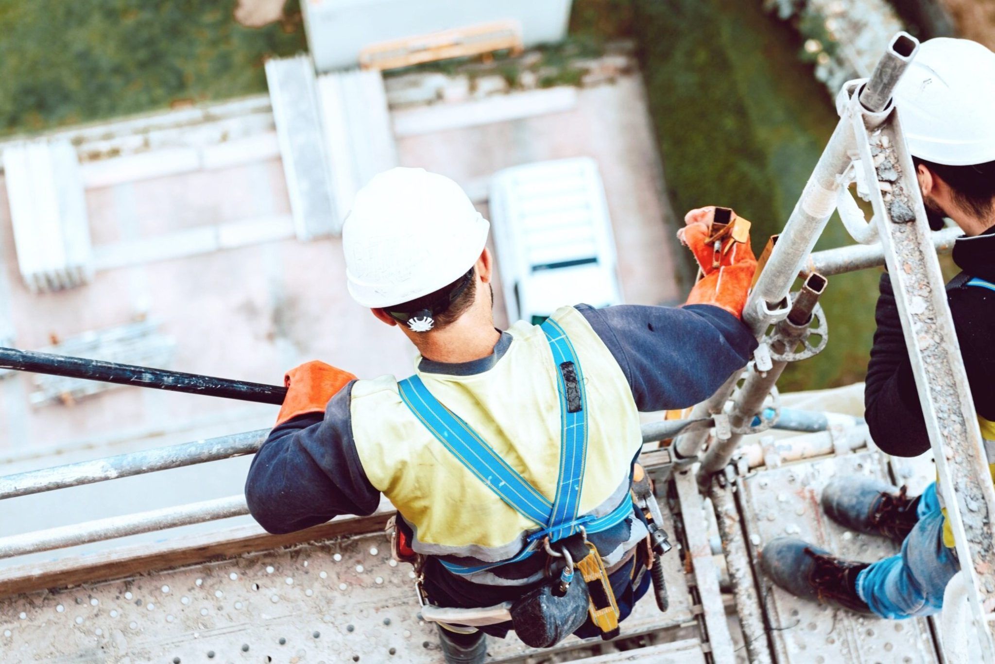 Employees with harnesses standing on scaffolding up high
