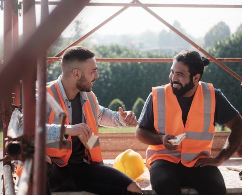Two workers with high vis on sitting between scaffolding