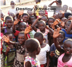 Destiny Rescue logo over a photo of a group of African children smiling and waving at the camera