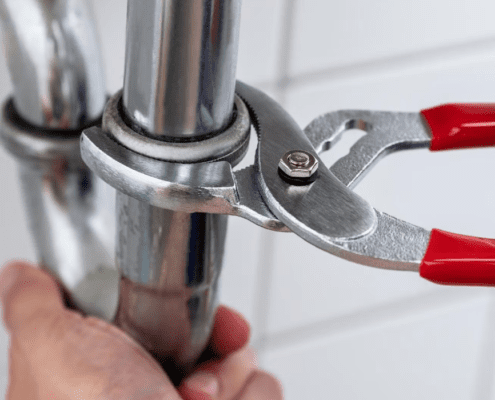 Close up of a play bets hands tinkering with a pipe with pliers