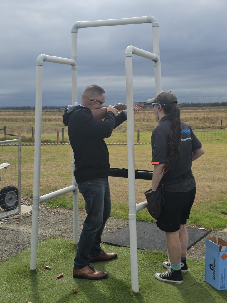 Member aiming gun at clay shooting day with instructor next to him