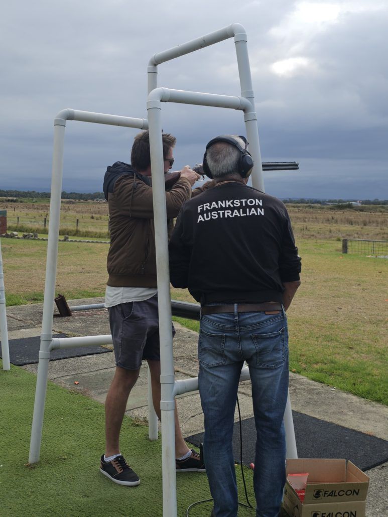 Man holding gun and instructor next to him clay shooting day