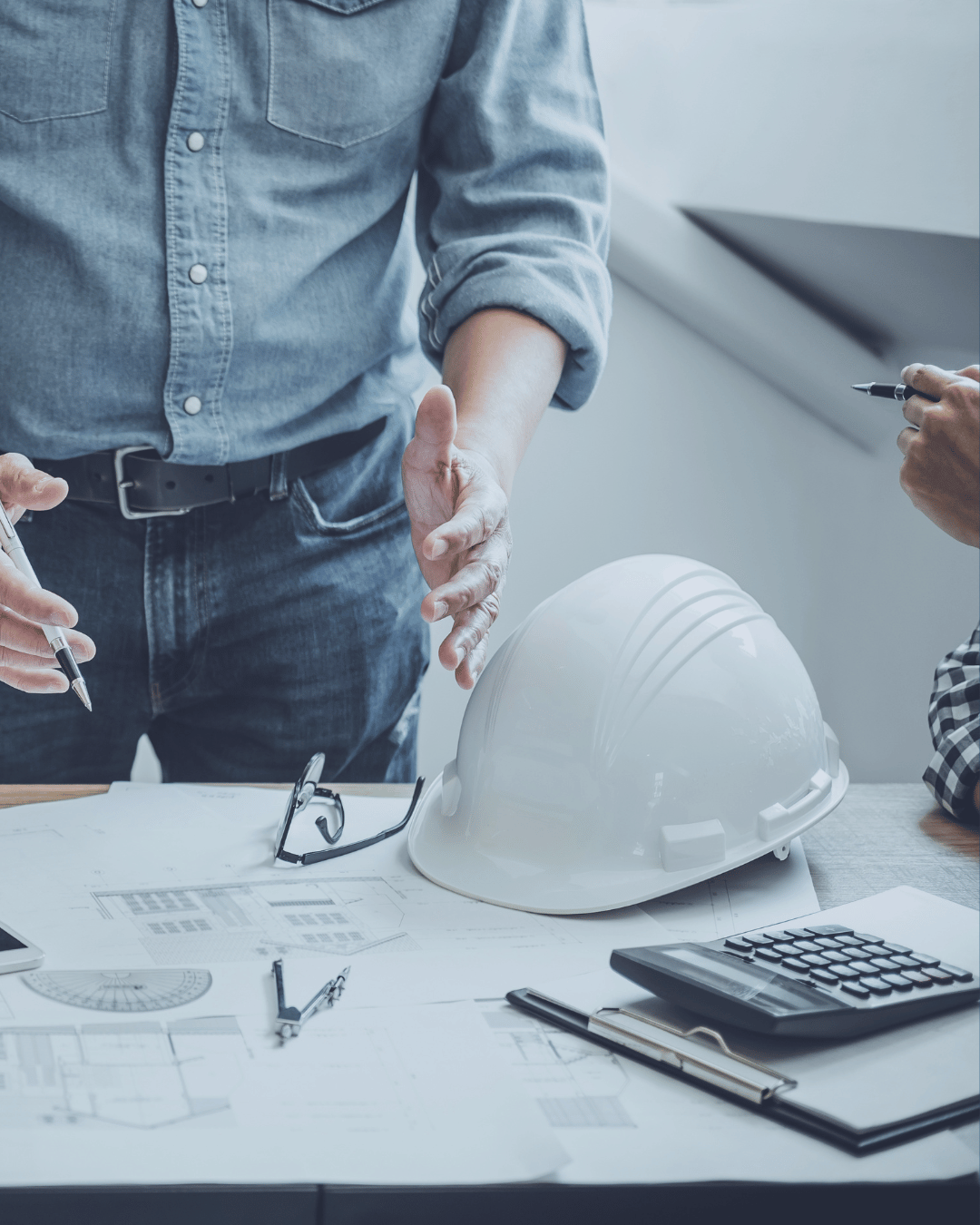 Paperwork on table and builders around with safety hat