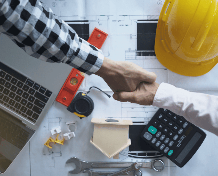 contractor hired shaking hands with builder equipment on table