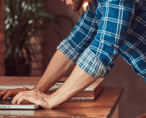 Newsletter Banner flannel shirt builder organising on laptop in workshop
